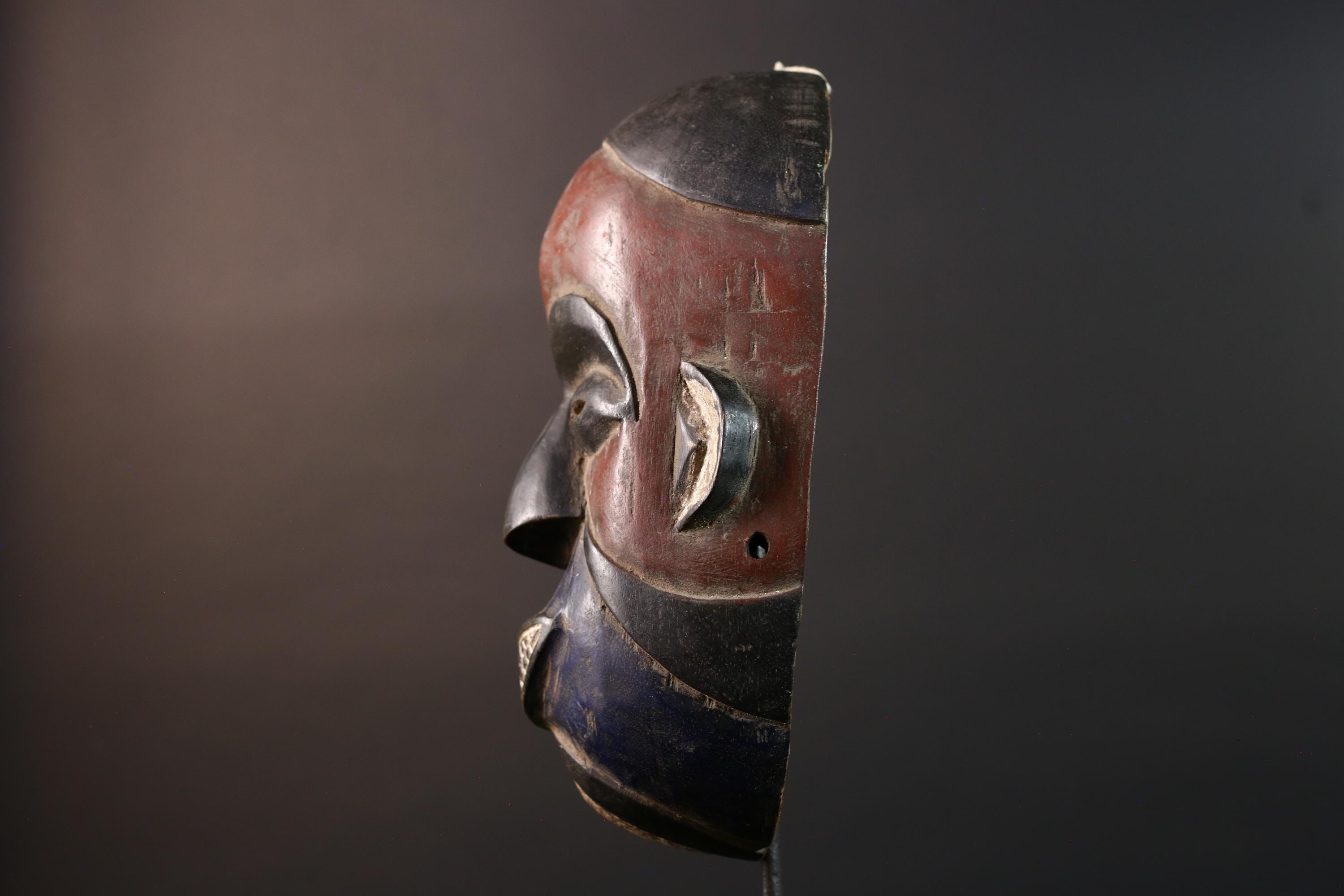 African wall decor Dan tribal mask with red white and blue split face carved features and symbolic teeth for expressive rustic display G5501
