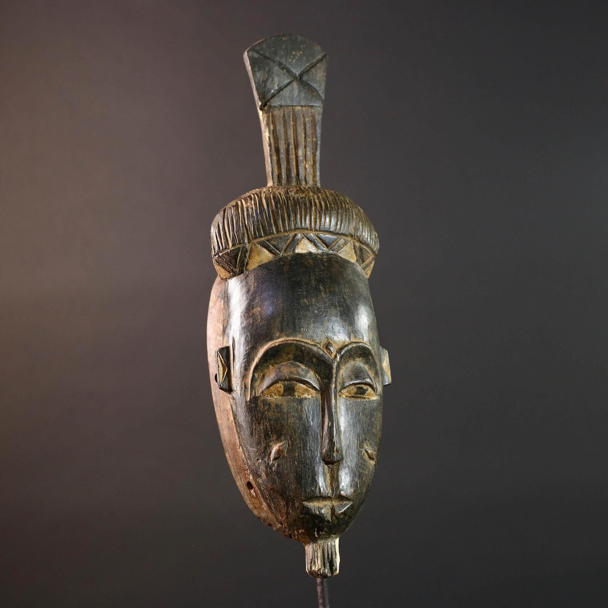 Africa tribal wall mask Baule carving with tall ridged crest narrow face and symbolic cheek marks for spiritual interior statement art G5502