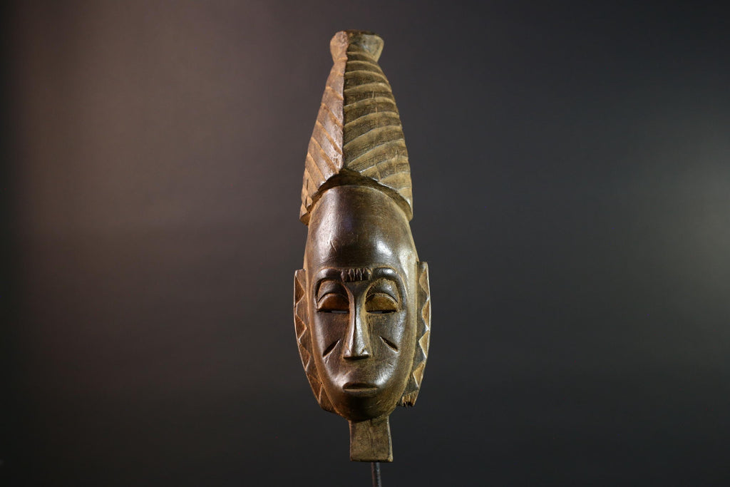 African mask Baule tribal art with long oval face, downcast eyes, vertical ridged crest, and carved cheek marks wall decor sculpture G5573