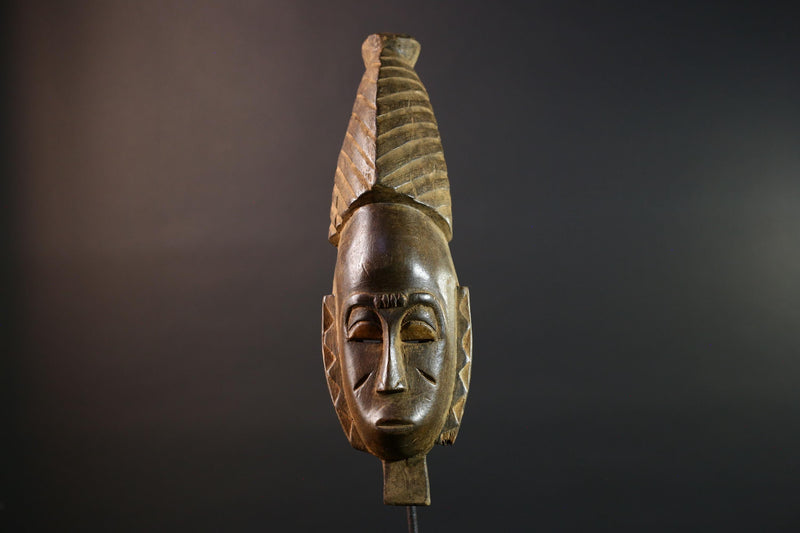 African mask Baule tribal art with long oval face, downcast eyes, vertical ridged crest, and carved cheek marks wall decor sculpture G5573