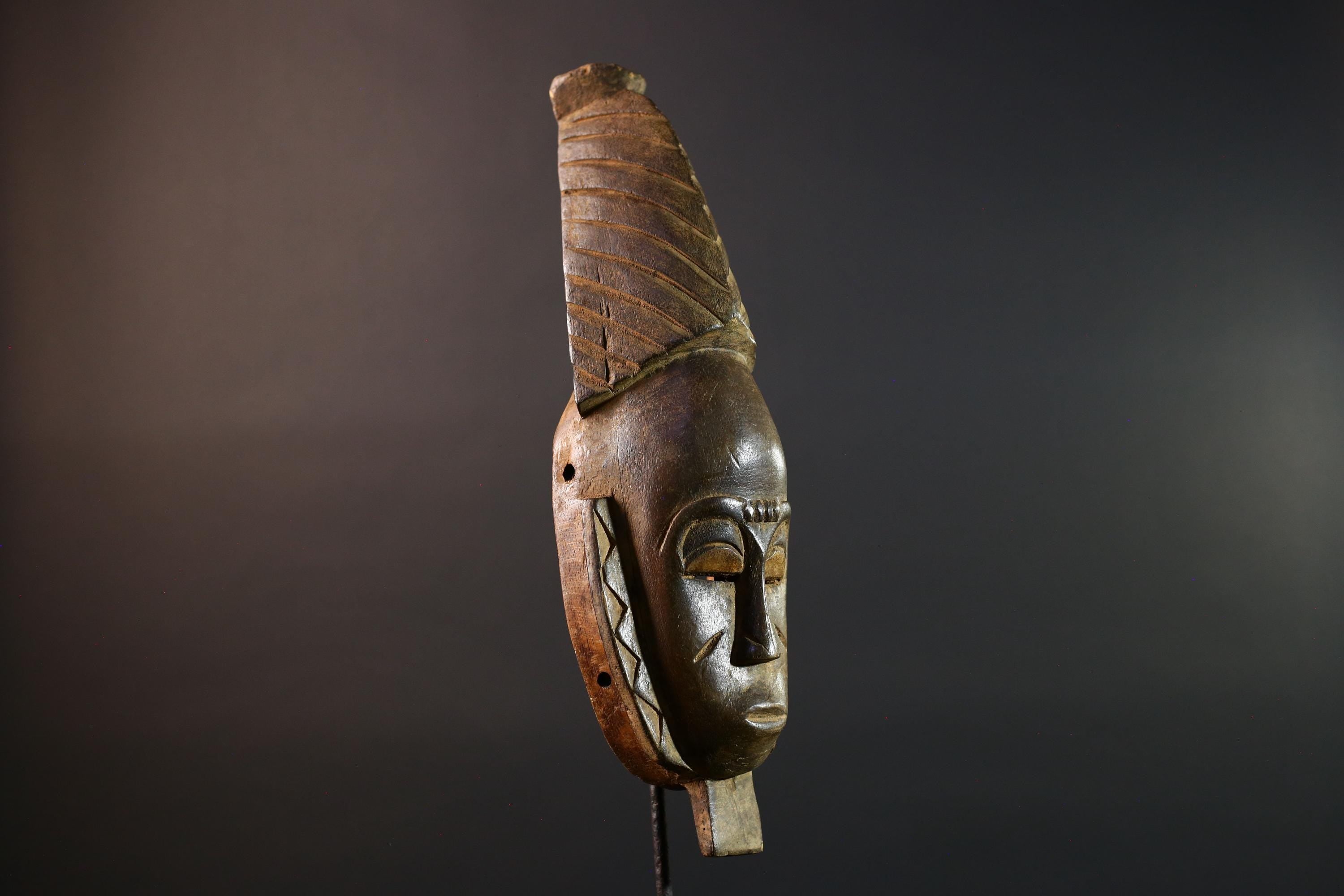 African mask Baule tribal art with long oval face, downcast eyes, vertical ridged crest, and carved cheek marks wall decor sculpture G5573