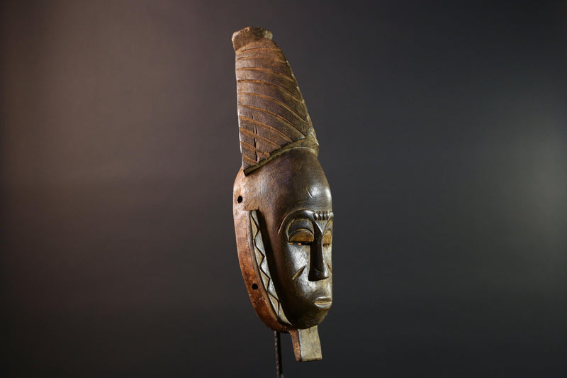 African mask Baule tribal art with long oval face, downcast eyes, vertical ridged crest, and carved cheek marks wall decor sculpture G5573
