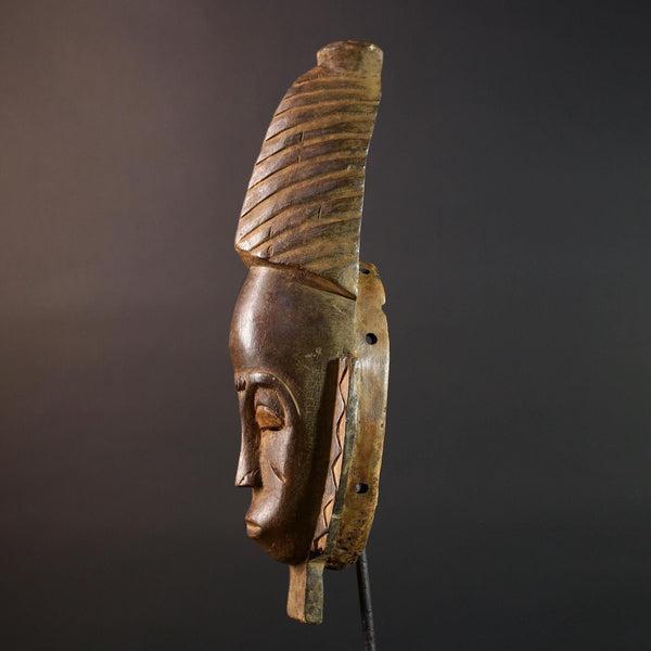 African mask Baule tribal art with long oval face, downcast eyes, vertical ridged crest, and carved cheek marks wall decor sculpture G5573