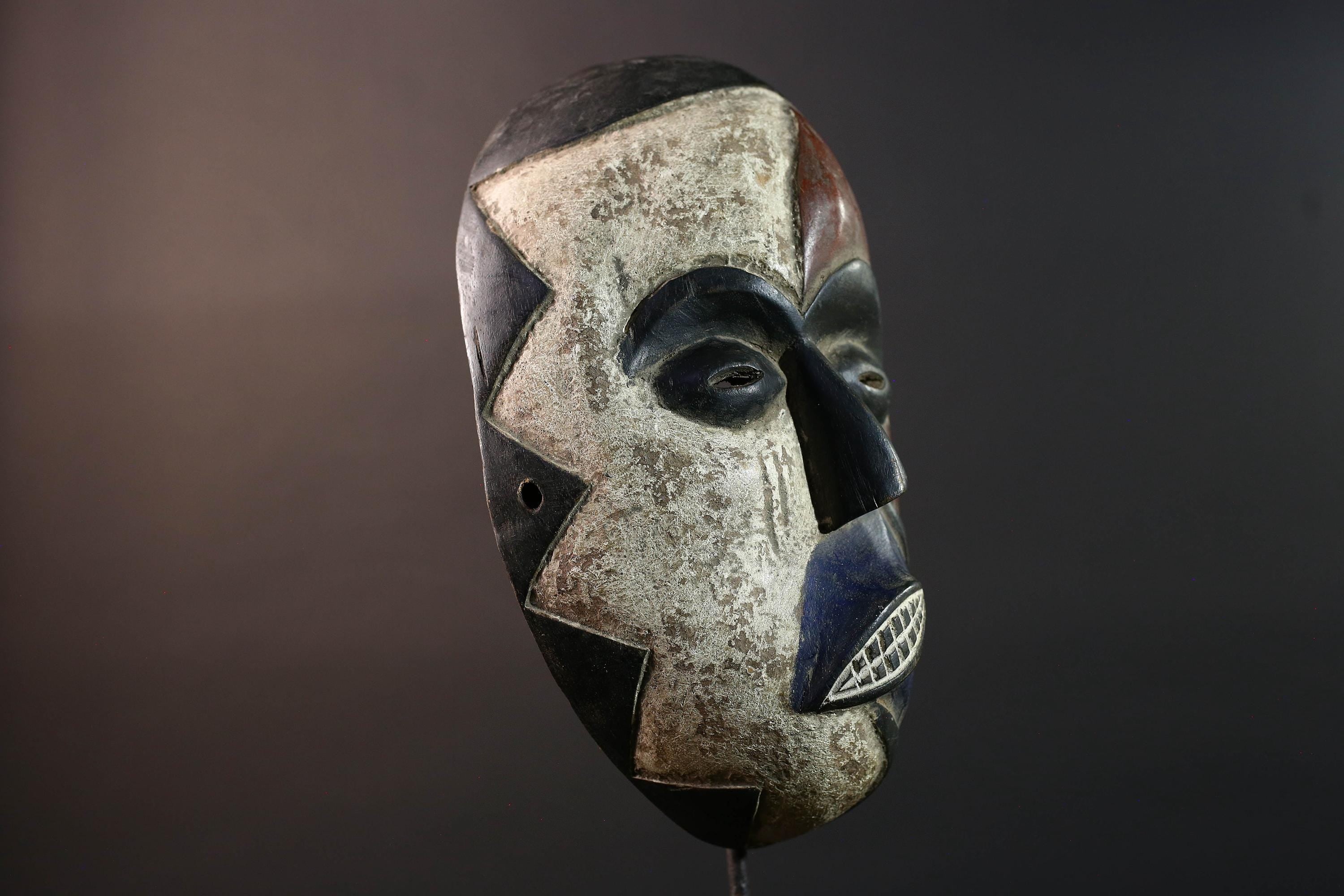 African wall decor Dan tribal mask with red white and blue split face carved features and symbolic teeth for expressive rustic display G5501