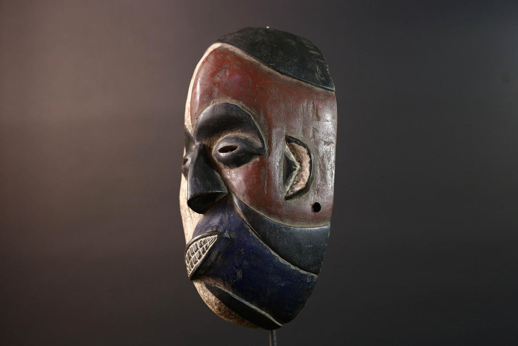 African wall decor Dan tribal mask with red white and blue split face carved features and symbolic teeth for expressive rustic display G5501