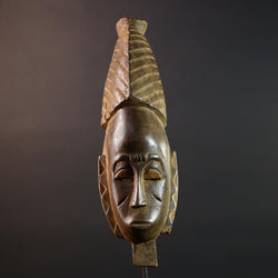 African mask Baule tribal art with long oval face, downcast eyes, vertical ridged crest, and carved cheek marks wall decor sculpture G5573